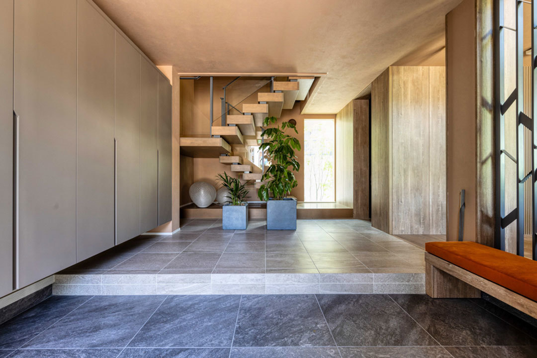 環八蒲田デシオ展示場_大容量の壁面収納を備えた玄関ホール。ダイナミックなオープン階段が印象的